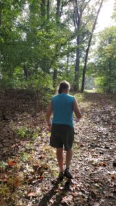 Woman walking in the woods in the summer with the light coming through the leaves.