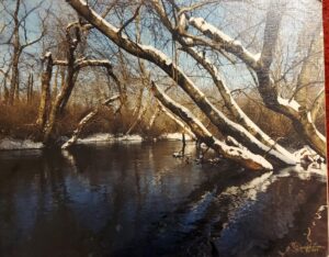 Trees covered with snow are reflected in the water near the banks of the stream