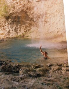 Holly waves as she sits in the middle of a hot mineral spring.